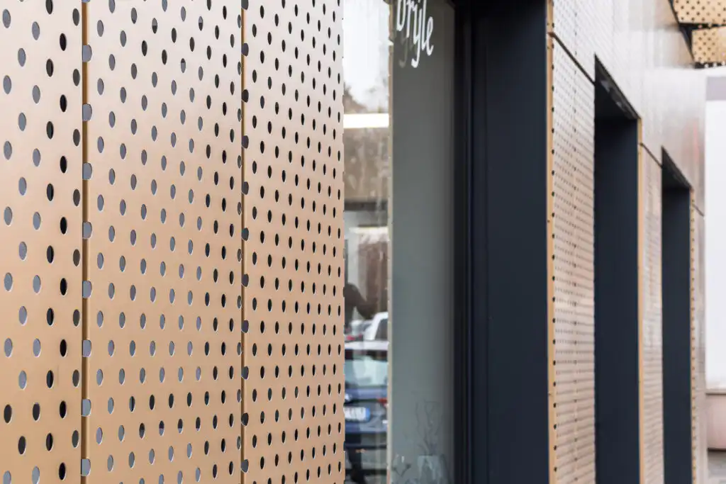 Celoplošná designová fasádní perforace s kruhovým vzorem na obchodu