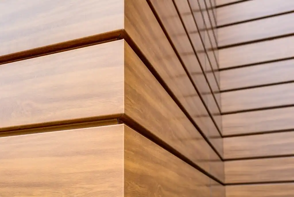 Detailní pohled na fasádní lamely v designu světlého dřeva se skrytými spoji.