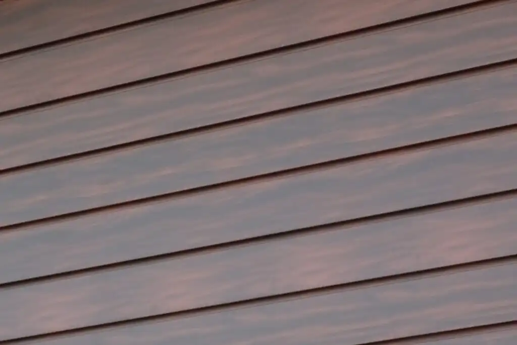 Textura fasádního plechu s reliéfní imitací struktury tmavého dřeva.