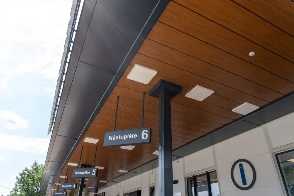 DEKMETAL obklad autobusové stanice v dřevěném dekoru s integrovaným osvětlením – moderní a odolné řešení fasádního a podhledového systému.