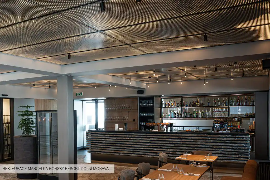 Podsvícený kazetový kovový podhled DEKMETAL s perforací ve tvaru mraku – designový a funkční prvek s integrovaným osvětlením.