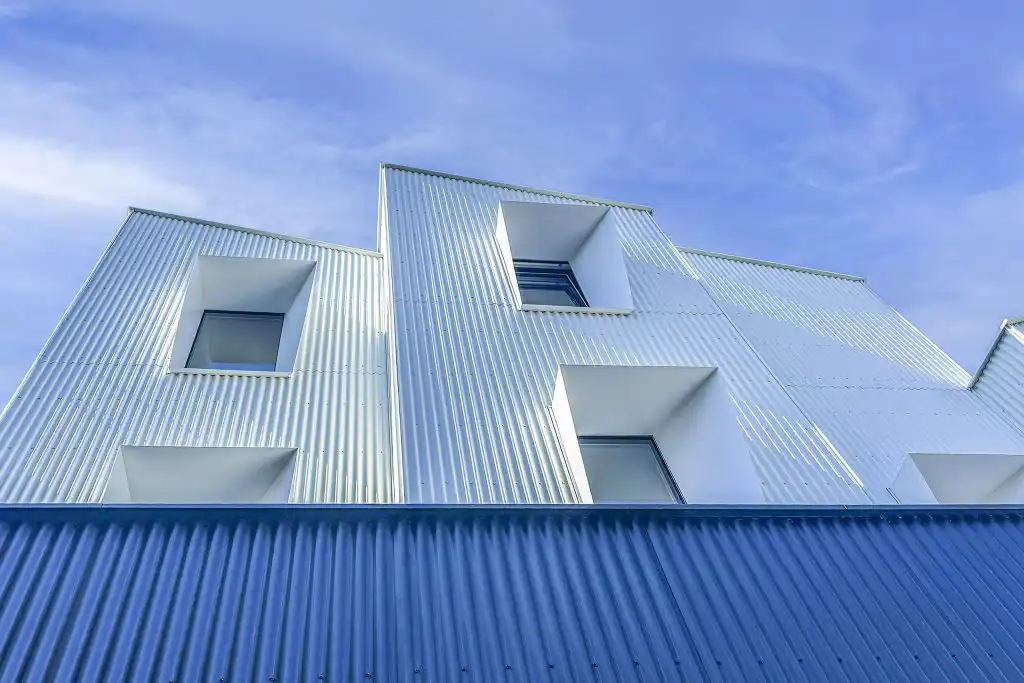 Svislý bílý fasádní profil DEKPROFILE CR pro odvětrávanou fasádu, detail svisle orientovaného kovového obkladu