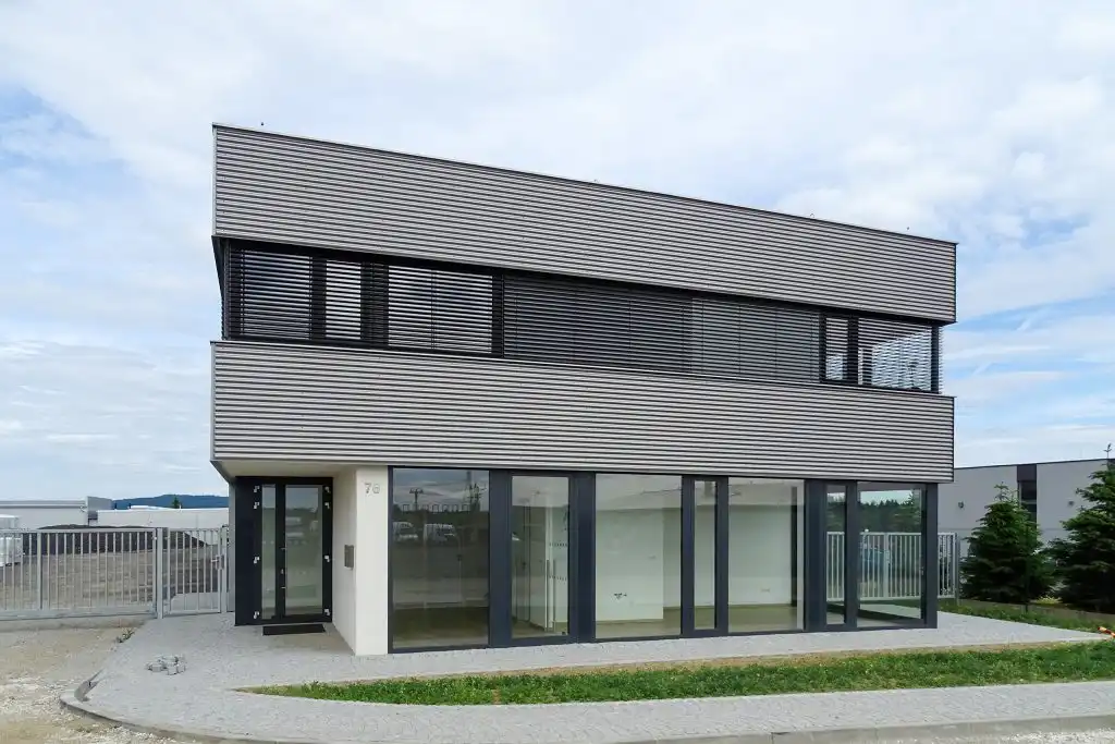 Vodorovně orientovaný plechový fasádní profil DEKPROFILE CR ve stříbrné barvě, instalovaný na průmyslové hale od DEKMETAL